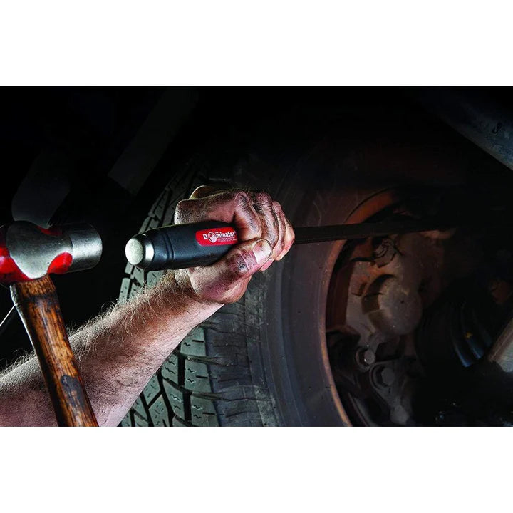 Curved Dominator Mayhew hand tool with ergonomic handle being used to pry near a vehicle tire, hammer in hand