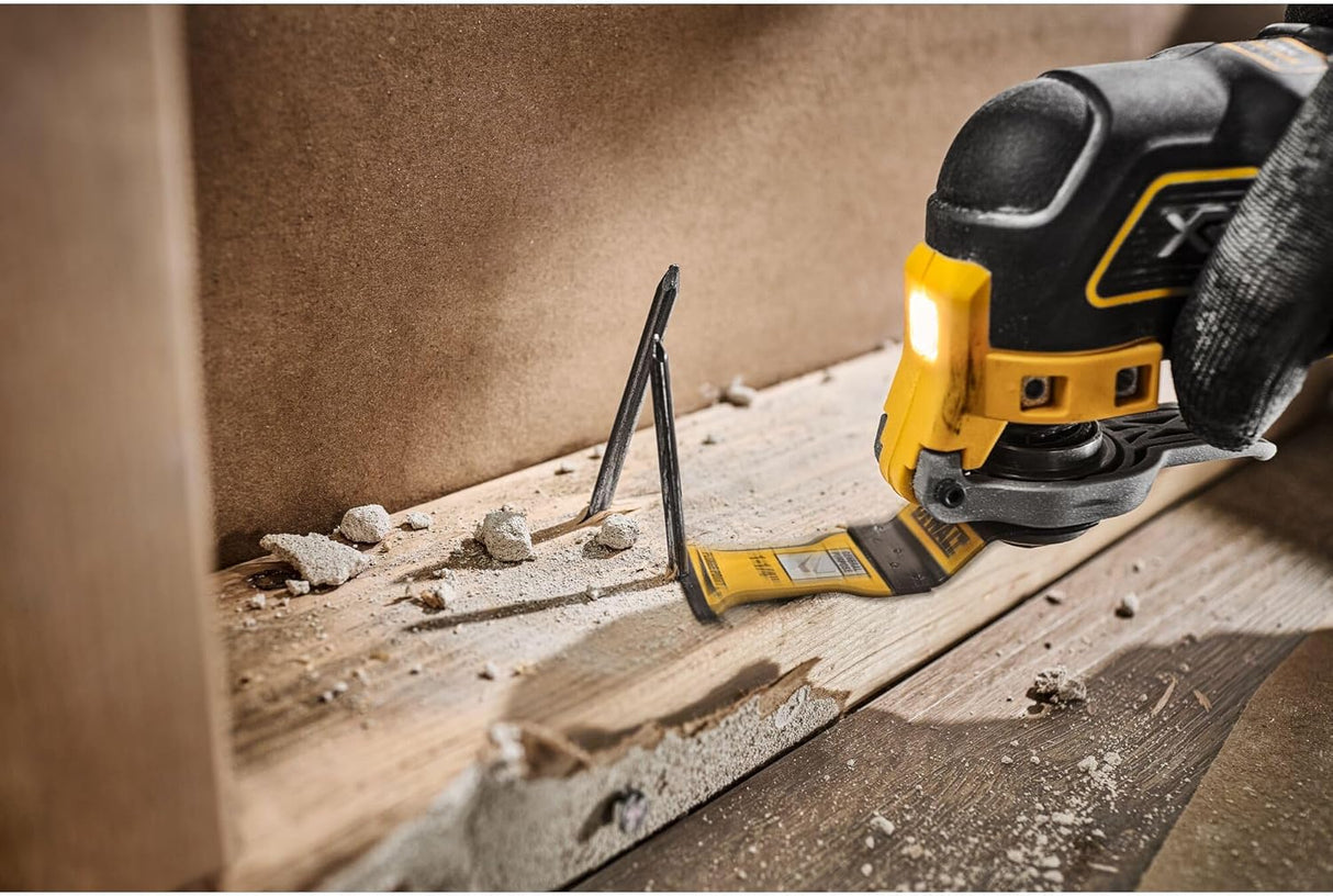 DeWalt oscillating plunge cut saw blade cutting through wood and nails with dust and debris visible