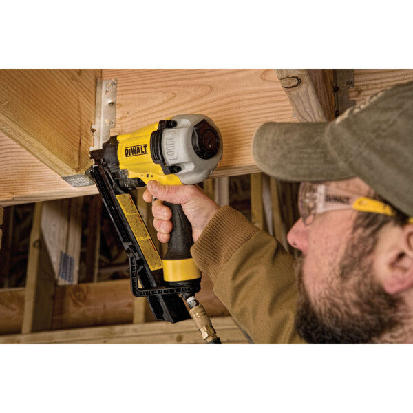 Worker using DEWALT DWMC150 pneumatic bracket nailer to fasten wood framing in construction setting