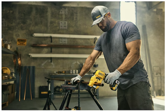 Man using Dewalt 20V MAX XR 1-1/4 inch copper pipe cutter in an industrial workshop setting