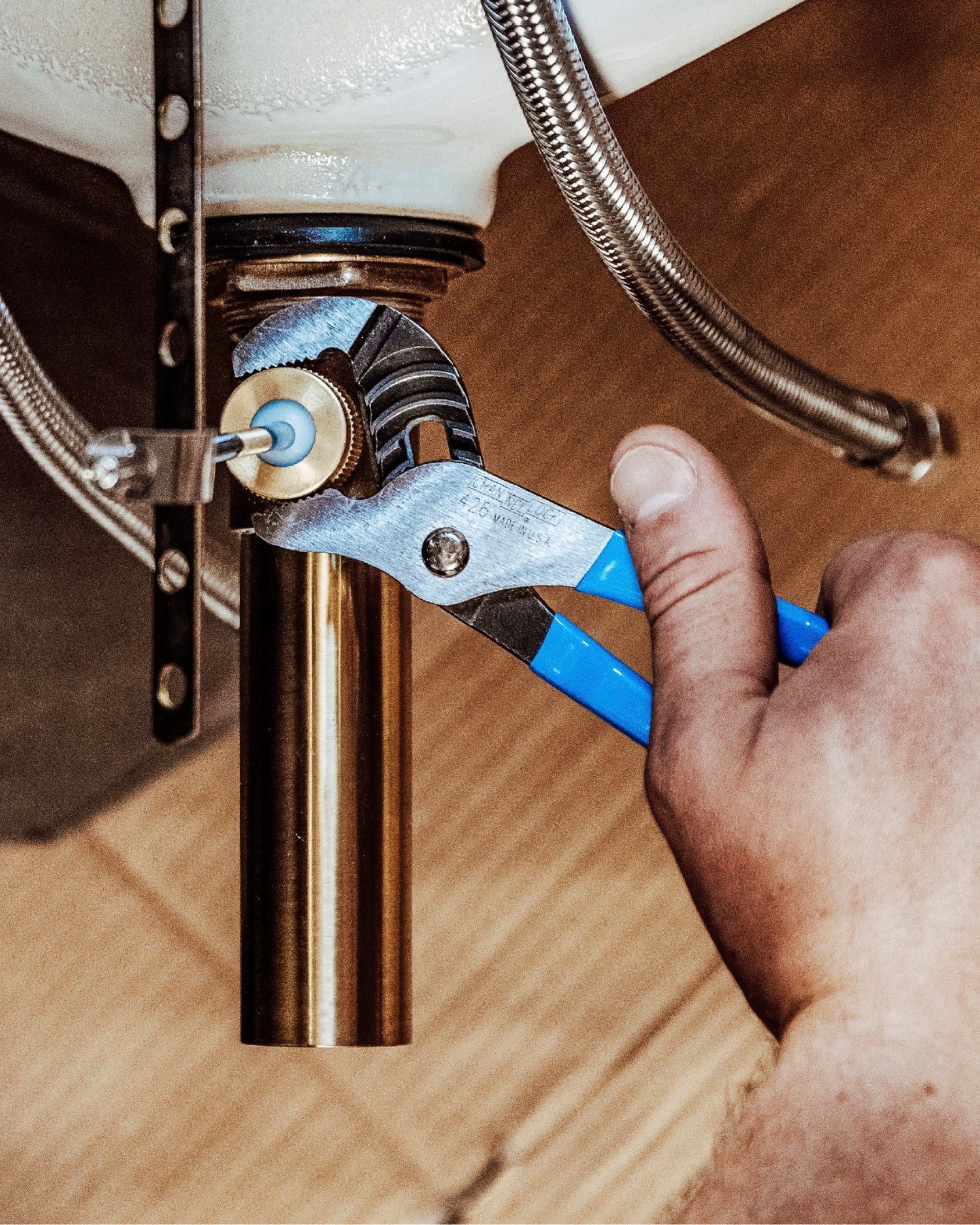 Channellock GS-3 groove joint pliers with blue handles gripping brass plumbing pipe fitting under sink installation