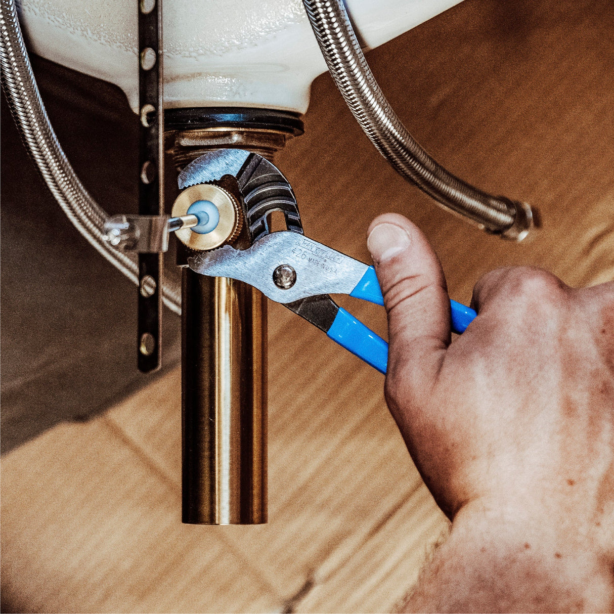 Channellock GS-3 groove joint pliers with blue handles gripping brass plumbing pipe fitting under sink installation