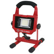 Portable 1500 lumen LED work lamp with 15W power, red metal frame, adjustable stand, and cushioned handle grip