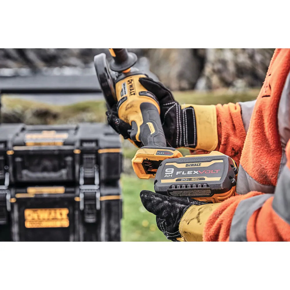 DeWalt FLEXVOLT 60V MAX cordless grinder with 9Ah battery and charger held by worker in safety gloves and jacket