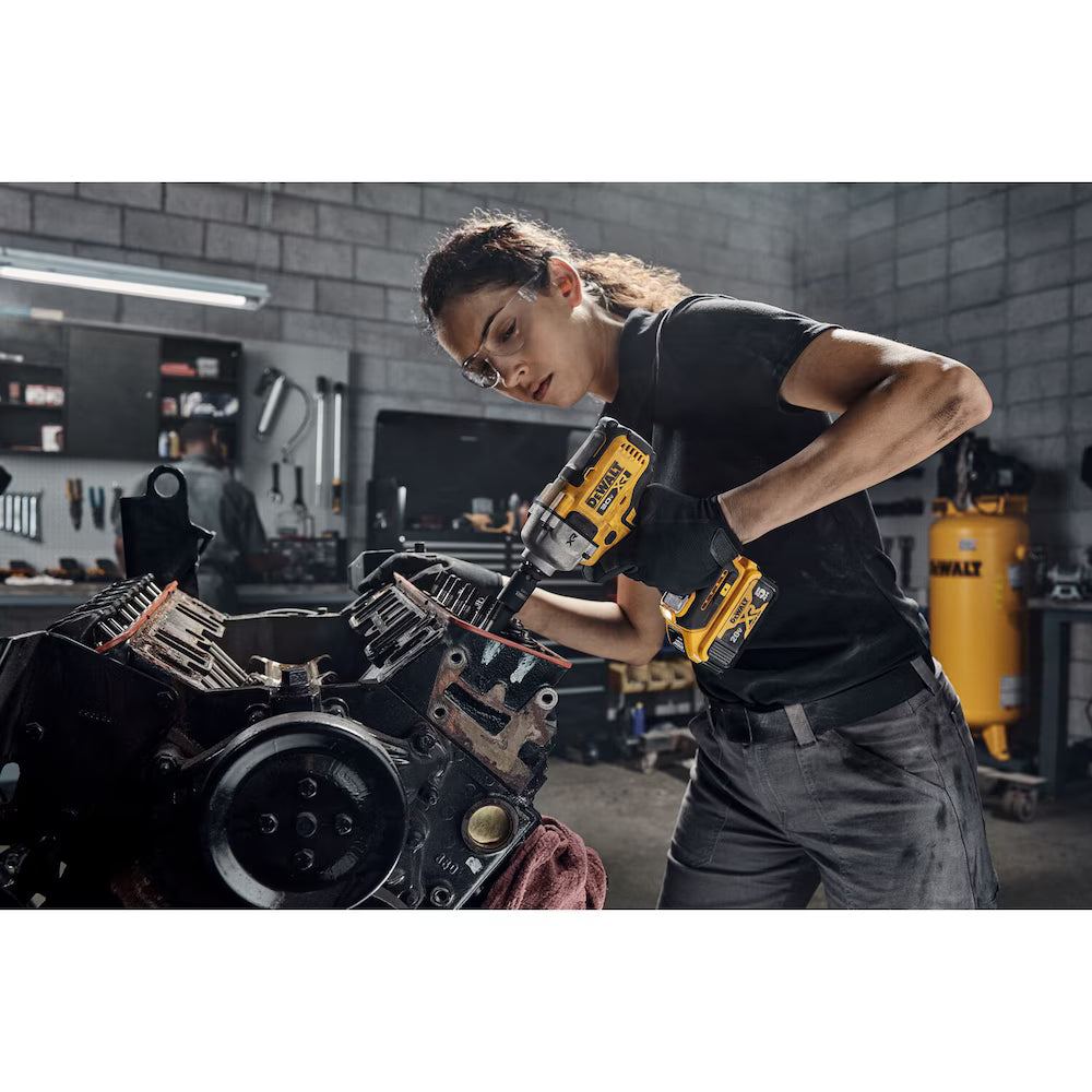Technician using yellow and black DEWALT 1/2" impact wrench on engine block in a garage workshop setting