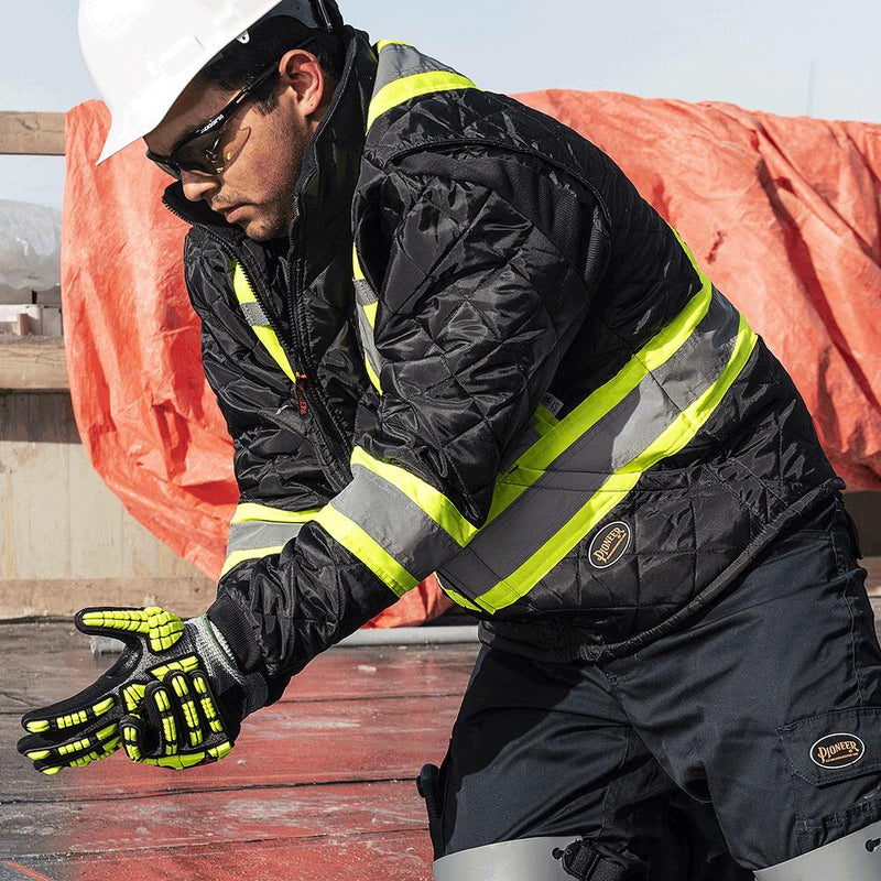 Construction worker wearing white hard hat, black reflective safety jacket, and protective gloves on job site